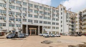 ein großes Gebäude mit auf einem Parkplatz abgestellten Autos in der Unterkunft GreenTree Alliance Hotel Yancheng Engineering College Dayangwan Scenic Area in Ti-pa-yung