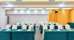 une salle de conférence avec des tables vertes et des chaises blanches dans l'établissement City Comfort Inn Yunfu Xinxing Juncheng Plaza, à Xinxing