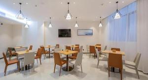 a dining room with wooden tables and chairs at City Comfort Inn Wuzhou Xijiang Thrid Bridge in Cangwu