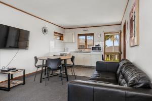 a living room with a couch and a table and a kitchen at Summit Motor Lodge in Tauranga