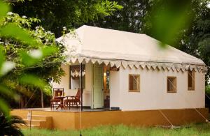 a small white house with a table and a chair at Varawal Leopard Camp in Mori Bera +15 photos