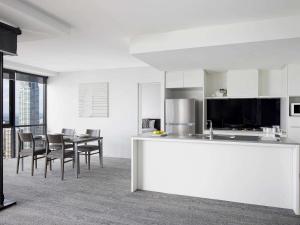 a kitchen and dining room with a table and chairs at Mantra Circle On Cavill in Gold Coast