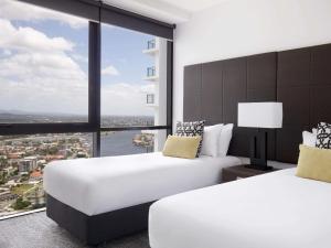 two beds in a hotel room with a large window at Mantra Circle On Cavill in Gold Coast +69 photos