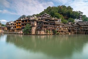 een groep houten gebouwen in het water bij Phoenix Geometry Light Accommodation in Fenghuang