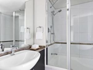 Un baño con bañera, lavabo y ducha. en Mantra Sydney Central, en Sídney 52 fotos más