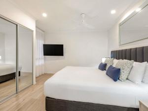 a bedroom with a white bed and a flat screen tv at Mantra Amphora in Palm Cove