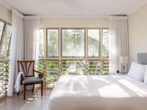 a bedroom with a large bed and a chair and windows at Mantra Amphora in Palm Cove