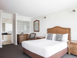 a bedroom with a large white bed and a bathroom at BreakFree Alexandra Beach in Alexandra Headland +75 photos