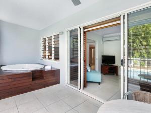 a room with a tub and a tv and a balcony at Mantra Aqueous on Port in Port Douglas