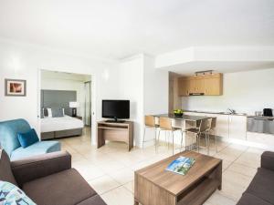 a living room with a couch and a table and a kitchen at Mantra Aqueous on Port in Port Douglas