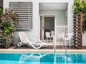 a patio with chairs and a table next to a pool at Mantra Aqueous on Port in Port Douglas