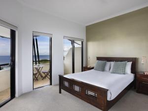 a bedroom with a large bed and a balcony at Mantra Esplanade in Cairns
