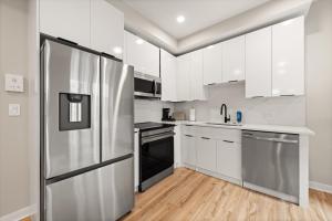 una cucina con mobili bianchi e un frigorifero in acciaio inossidabile di Soho DC Lux 1BD Apartment a Washington Altre 10 foto