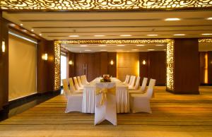 a conference room with a long table with white chairs at Dolphin Hotel in Visakhapatnam