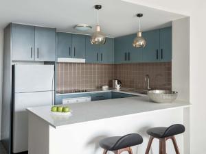 a kitchen with blue cabinets and a white refrigerator at Mantra Chatswood in Sydney