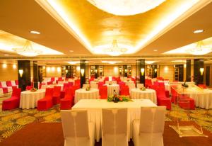 a banquet hall with white tables and red chairs at Dolphin Hotel in Visakhapatnam