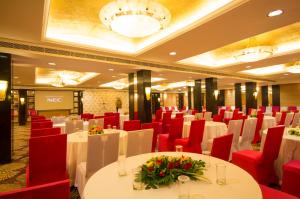 a banquet hall with white tables and red chairs at Dolphin Hotel in Visakhapatnam