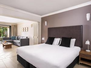 a hotel room with a large bed and a couch at Mantra Heritage in Port Douglas