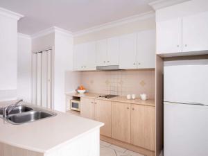 a white kitchen with a sink and a refrigerator at Mantra Heritage in Port Douglas +32 photos