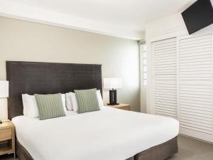 a bedroom with a large white bed with a black headboard at Mantra Mooloolaba Beach in Mooloolaba +76 photos