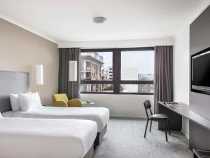 a hotel room with two beds and a television at Mantra Parramatta in Sydney +70 photos