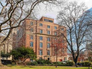 Un gran edificio de ladrillo con árboles delante. en Mantra One Sandy Bay Road, en Hobart