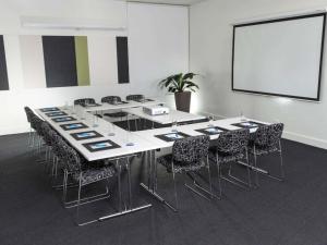 ein Konferenzraum mit Tisch und Stühlen und einer Leinwand in der Unterkunft Mantra Broadbeach on the Park in Gold Coast + 53 Fotos