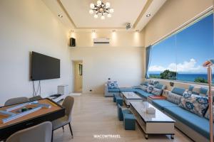 ein Wohnzimmer mit einer blauen Couch und einem großen Fenster in der Unterkunft 小琉球暮光停琉海景包棟民宿 in Xiaoliuqiu