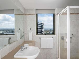 a bathroom with a sink and a shower with a window at Mantra Sun City in Gold Coast +57 photos