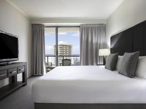 a bedroom with a large white bed and a large window at Mantra Sun City in Gold Coast