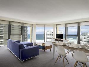 Una sala de estar con un sofá azul y una mesa. en Mantra Sun City, en Gold Coast
