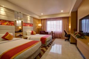 a hotel room with two beds and a desk at Dolphin Hotel in Visakhapatnam