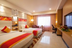 a hotel room with two beds and a television at Dolphin Hotel in Visakhapatnam