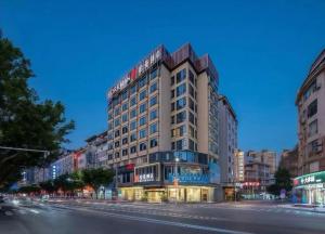 ein hohes Gebäude in einer Stadtstraße bei Nacht in der Unterkunft Borrman Hotel Chongqing Hechuan High-speed Railway Station District Government in Hechuan