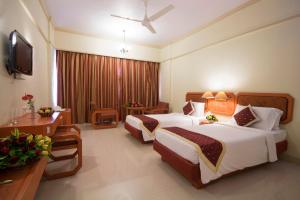 a hotel room with two beds and a television at Dolphin Hotel in Visakhapatnam