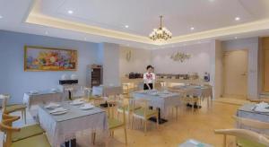 Eine Frau steht in einem Zimmer mit Tischen und Stühlen in der Unterkunft Vienna Hotel Jinjiang Bus Passenger Station in Jingjiang