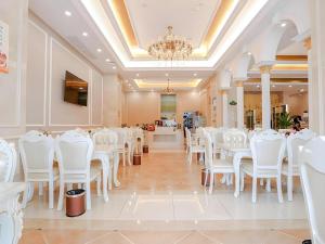 a room with white chairs and tables and a chandelier at Vienna Hotel Yueyang East Station in Yueyang