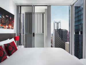 Un dormitorio con una cama blanca y una ventana grande. en Mantra Midtown, en Brisbane 49 fotos más
