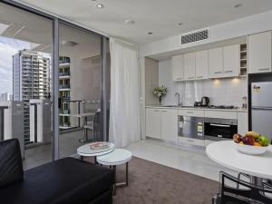 une cuisine et un salon avec des armoires et des tables blanches dans l'établissement Mantra Midtown, à Brisbane