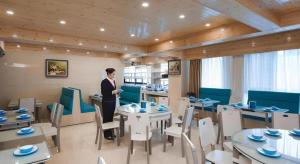 une femme debout dans un restaurant avec des tables et des chaises dans l'établissement Vienna Hotel Shandong Liaocheng High-Tech Zong Yueji Park, à Liaocheng