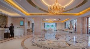 Ein Mann steht in einem großen Raum mit einem Kronleuchter in der Unterkunft Vienna Hotel Guangdong Shaoguan Shaonan Avenue in Leyuan