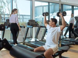 a man sitting on a gym machine lifting weights at Mercure Dubai Deira in Dubai