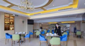 a woman standing at a table in a restaurant at Vienna Hotel Anhui Lujiang International Building Materials Market Wuzhong in Lujiang