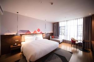 ein Schlafzimmer mit einem großen weißen Bett und einem Stuhl in der Unterkunft Borrman Hotel Baise High-speed Railway Station Hengning Plaza in Qitang + 128 Fotos