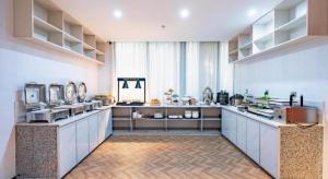 eine große Küche mit weißen Theken und einem großen Fenster in der Unterkunft Borrman Hotel Wuzhou College Fumin Road in Wuzhou