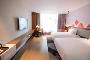 ein Hotelzimmer mit zwei Betten und einem Fernseher in der Unterkunft Borrman Hotel Baise High-speed Railway Station Hengning Plaza in Qitang