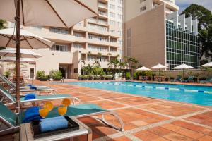 a pool at a hotel with chairs and umbrellas at Somerset Chancellor Court in Ho Chi Minh City