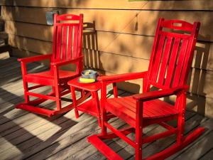 two red chairs sitting next to each other on a porch at Cabin on Rainbow - Spa - Fireplace - BBQ - EV - Save with Longer Stay! in Big Bear City