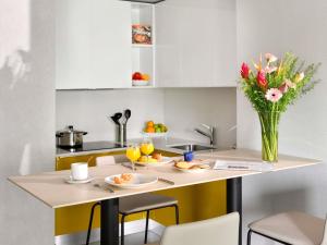 a kitchen with a table with a vase of flowers at Aparthotel Adagio Abidjan Marcory in Abidjan