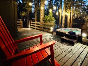 a red bench sitting on a wooden deck with a hot tub at Cabin on Rainbow - Spa - Fireplace - BBQ - EV - Save with Longer Stay! in Big Bear City +39 photos